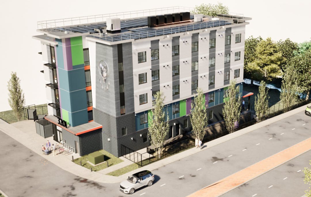 Modern four‑storey apartment building with colorful accents, tall trees, and cars along the street.