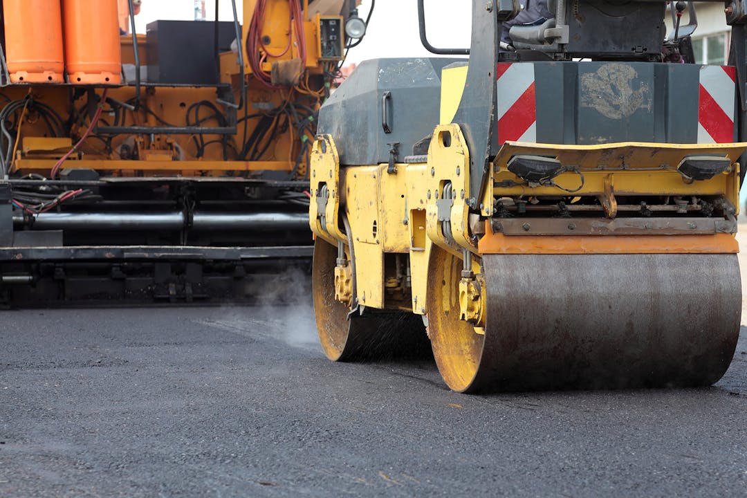 Paving equipment rolling over fresh asphalt.