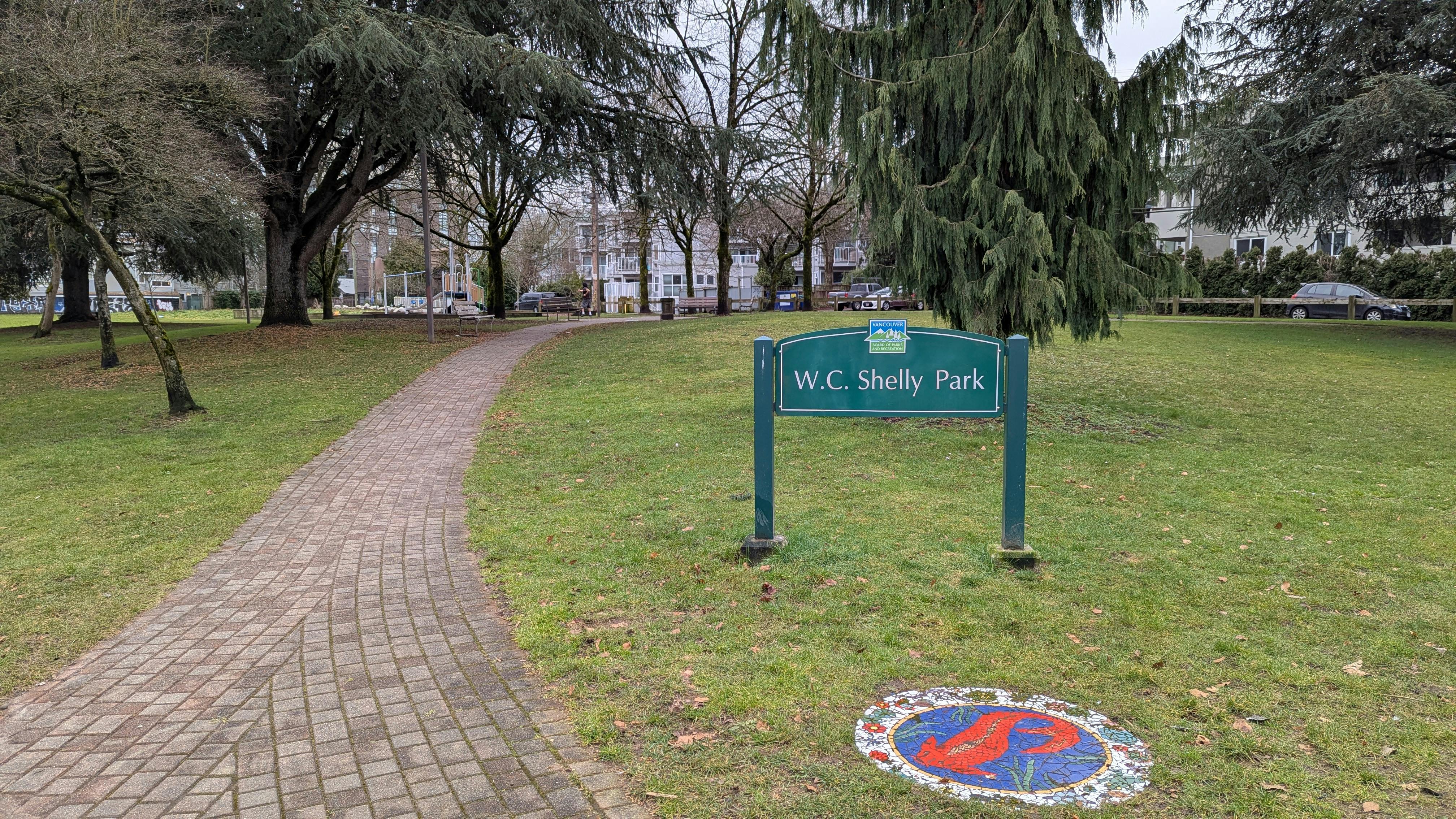 Image of park entry path leading to the centre of the park, with park signage and mosaic