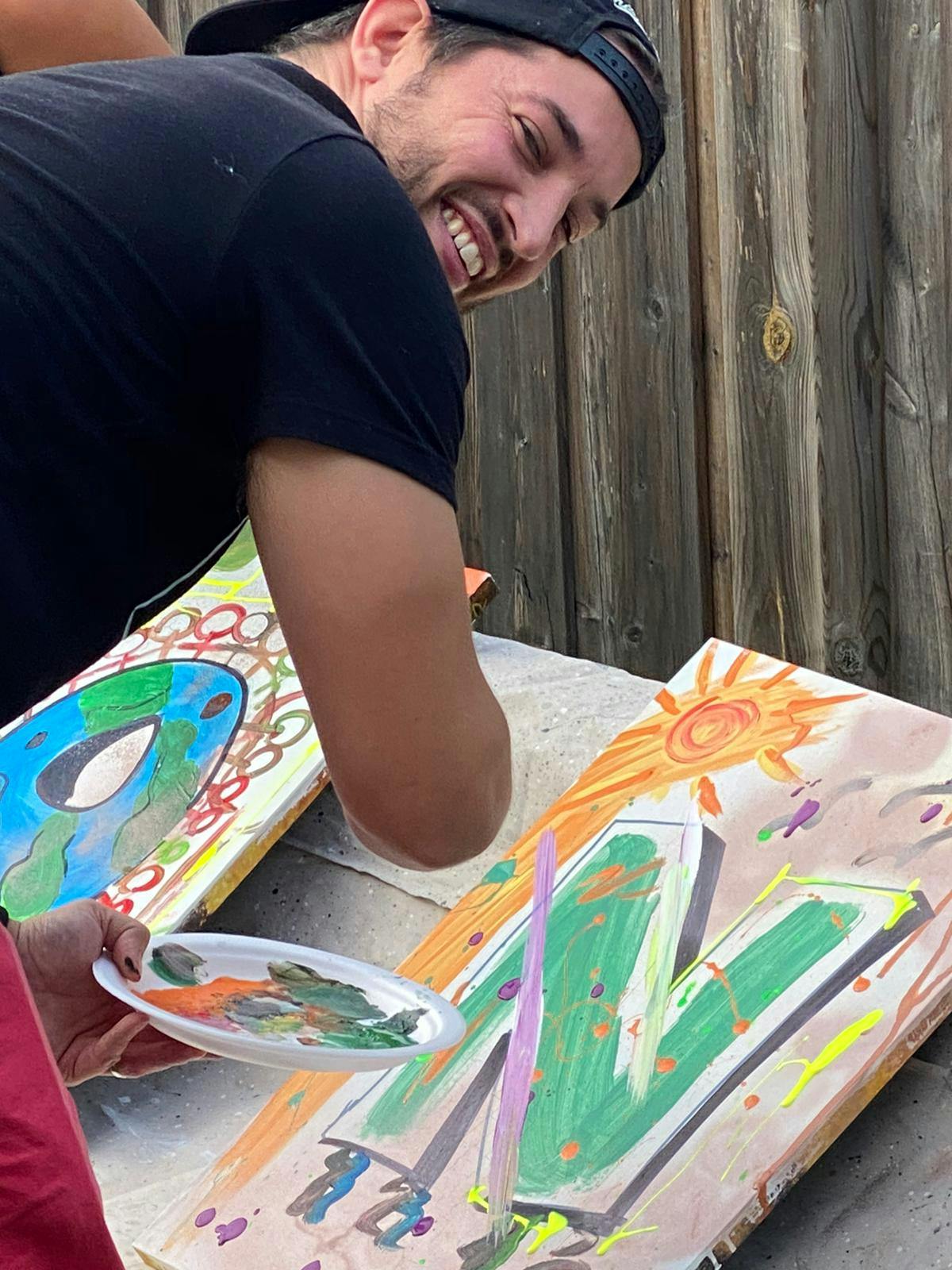 Participant smiling while painting at canvas.