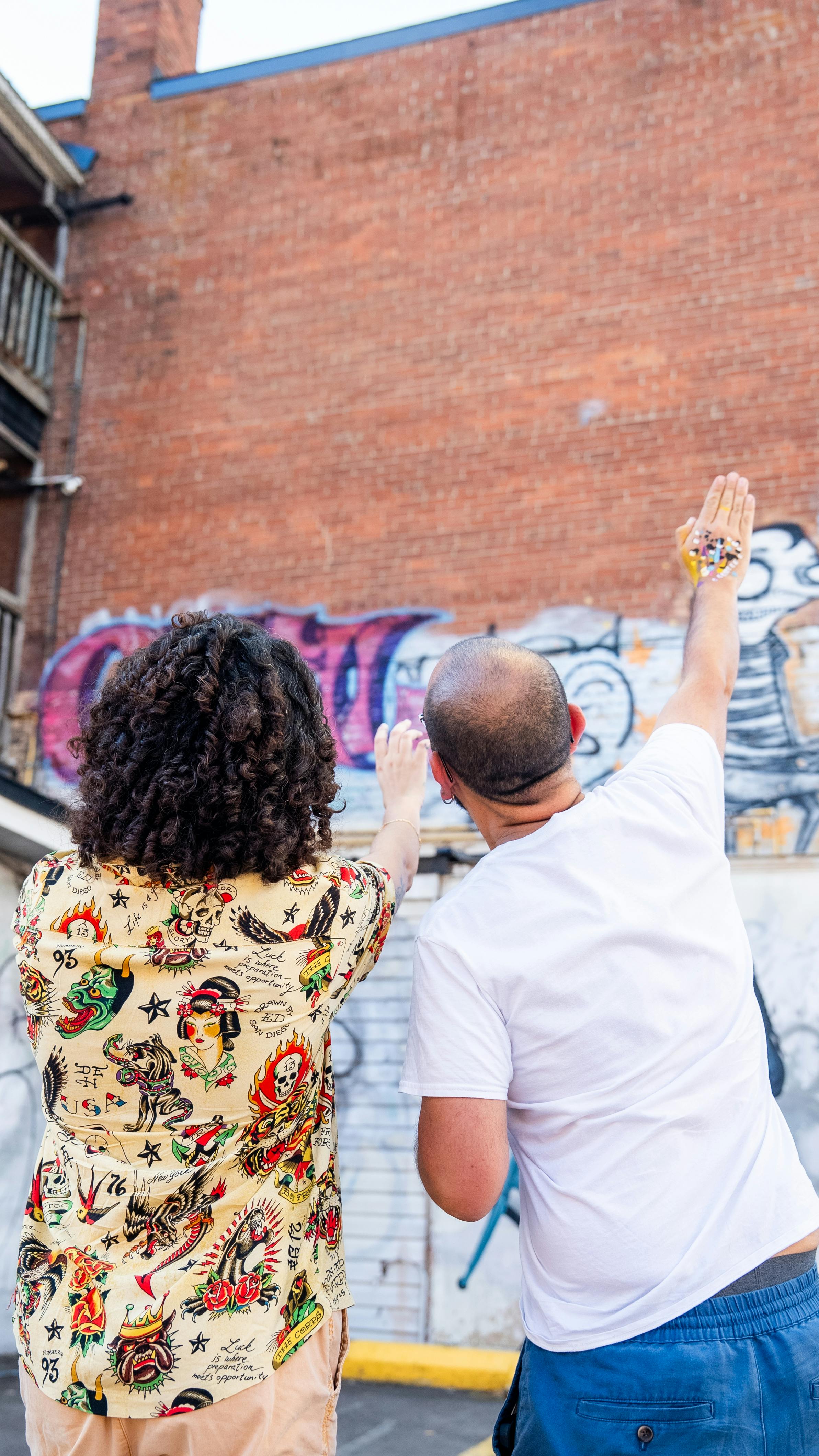 Two people pointing and looking at a mural.