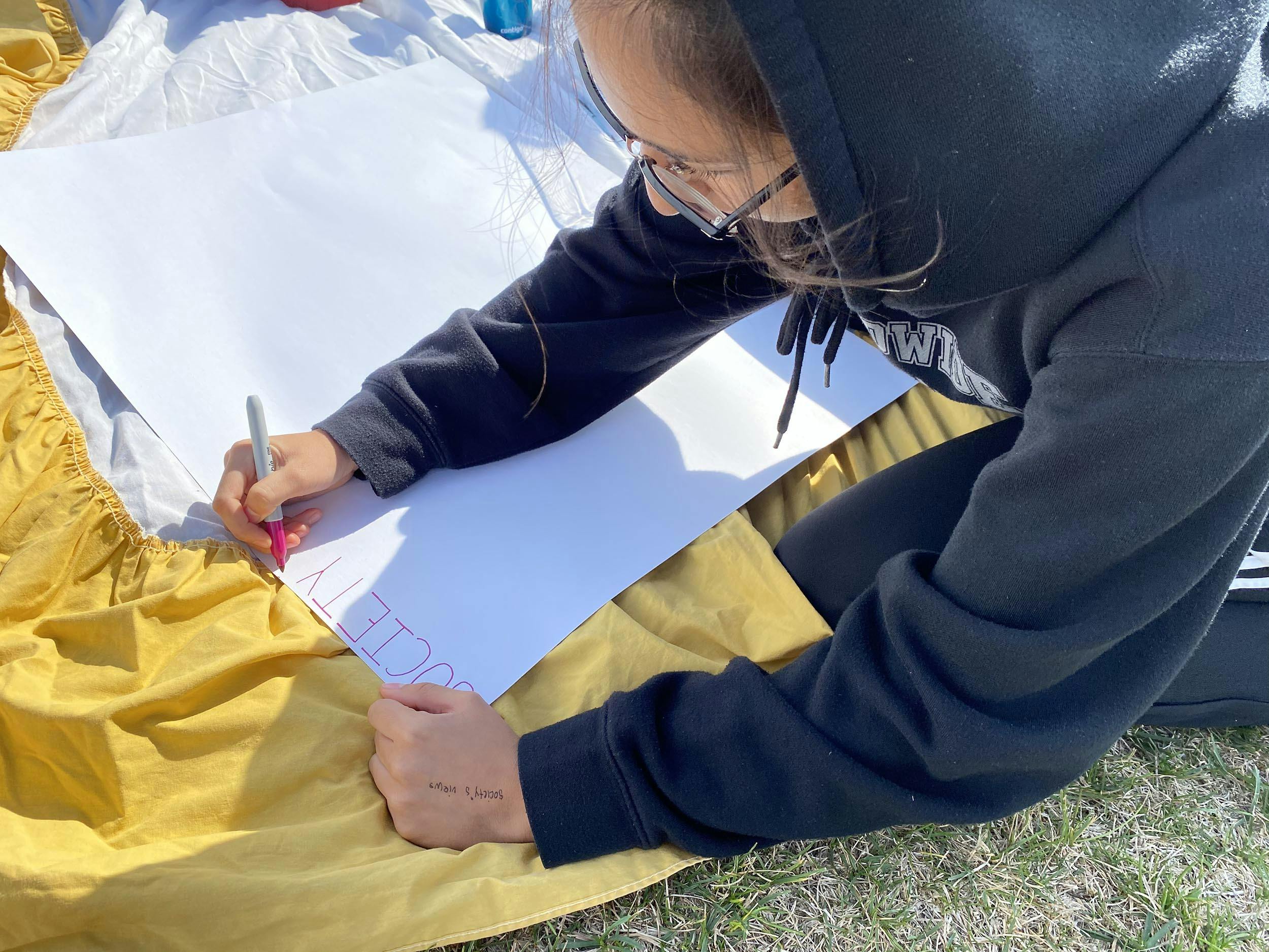 Young person writing words on their collage. 