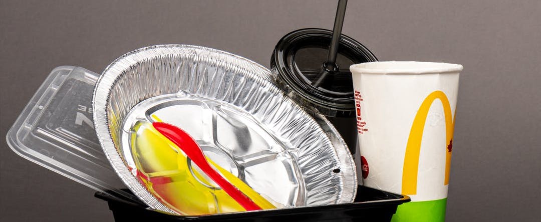 Single-use items including takeout container, straw, utensils, and to-go cup