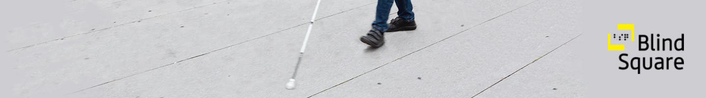 A cropped photo of feet and the bottom half of a white cane on concrete. The BlindSquare logo is on the right.