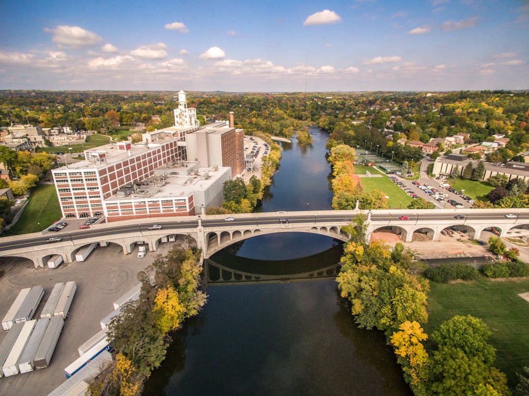 Aerial view of central Peterborough on east side of Otonabee River facing north including Quaker factory, park & bridge