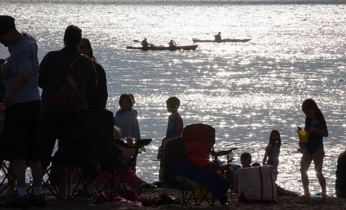 Les nageurs et les kayakistes profitent du coucher de soleil au parc Dominion