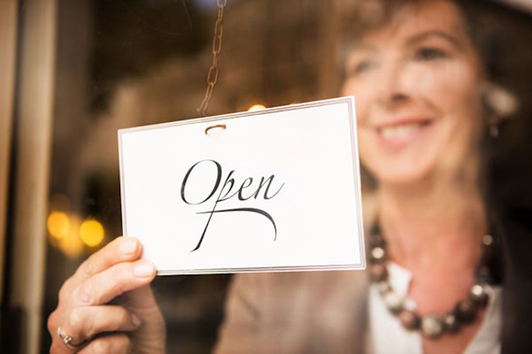 Woman putting open sign on business window