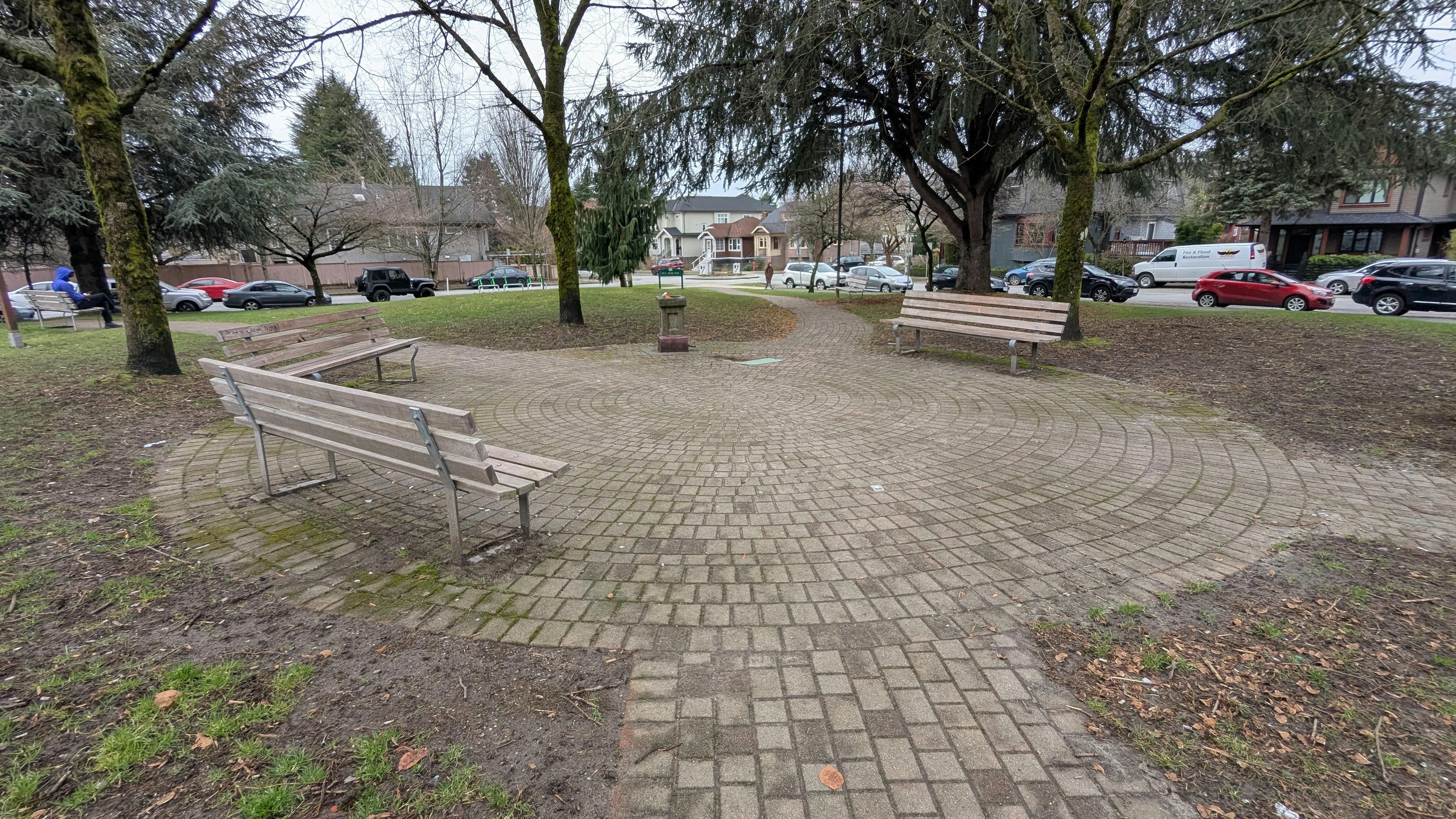Image of a paved circle with three benches and water fountain lining the perimeter.
