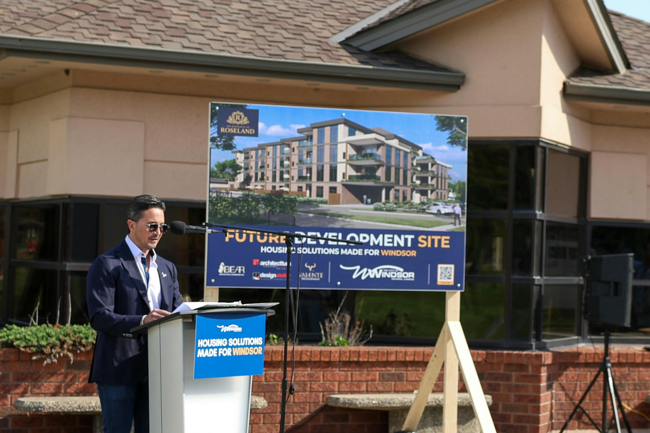 Peter Valente speaking at the podium at the announcement of the new Housing Solutions Made for Windsor "Residence at Roseland" site.