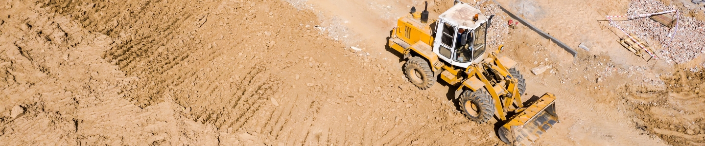 A backhoe grading fill on a property. 