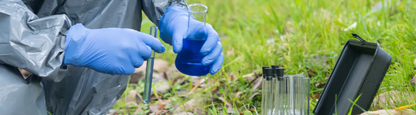 A forensic scientist wearing Personal Protective Equipment tests samples outdoors