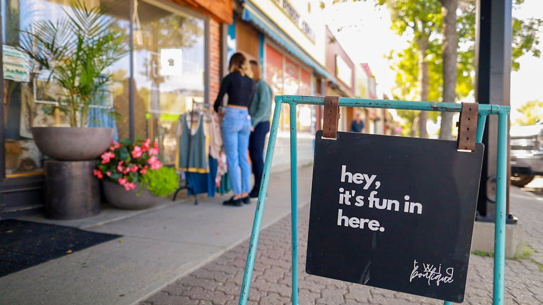 Shopping downtown Camrose during the summer with a sign saying "hey, it's fun in here" in the foreground.