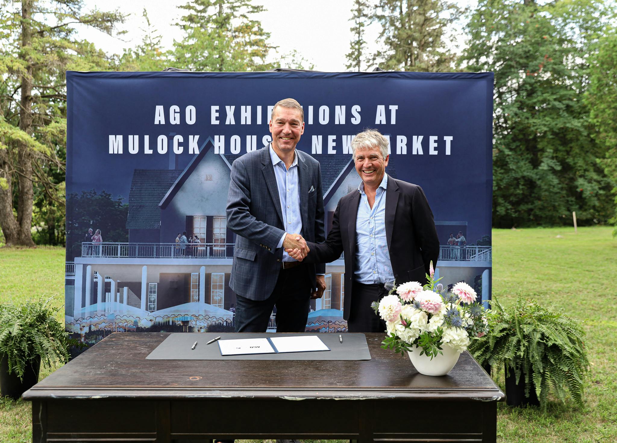Newmarket Mayor John Taylor and Stephan Jost from the Art Gallery of Ontario (AGO) sign a memorandum of understanding on top of Sir William Mulock's desk to bring AGO exhibitions to the Mulock House at the landmark Mulock Park when it opens in 2025.