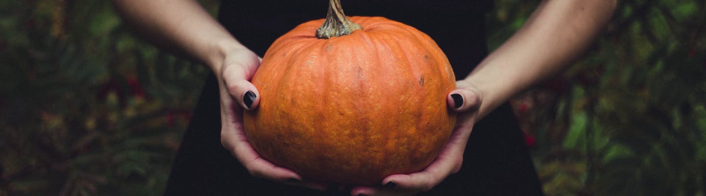 Woman with black nails holds pumpkin