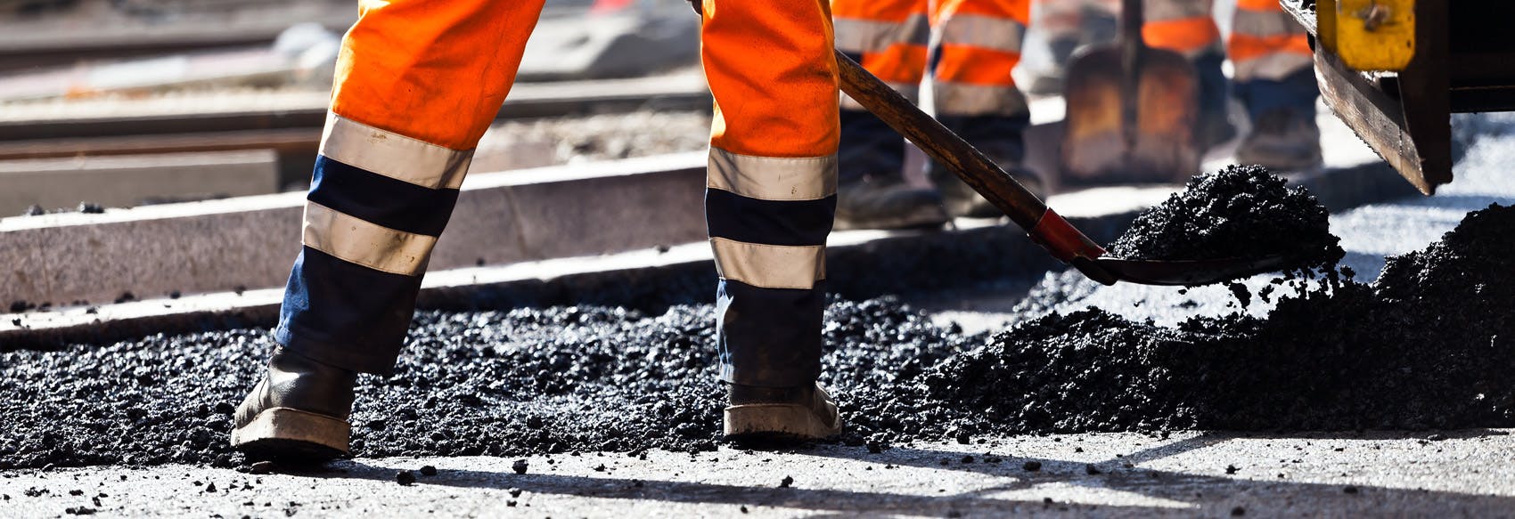 Construction worker shoveling asphalt 