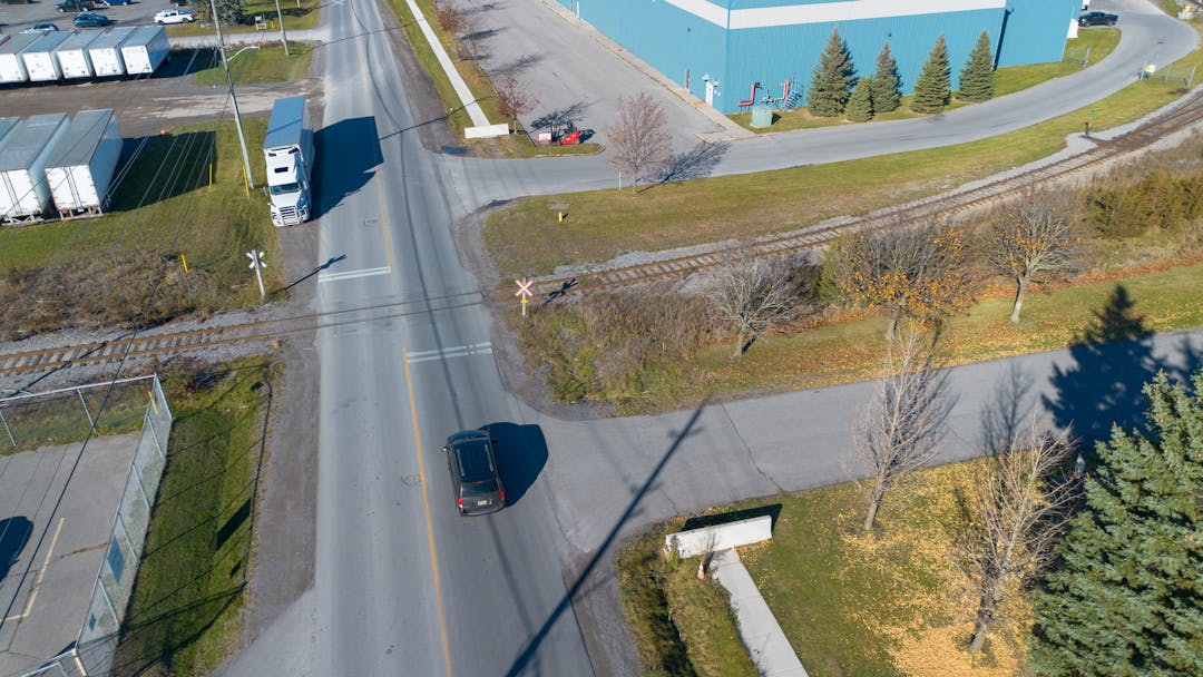 Photo of a road with an incomplete sidewalk that stops before a train track crossing.
