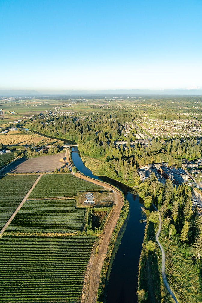 Aerial view of forest and meadow parkland, the river, and agricultural fields.