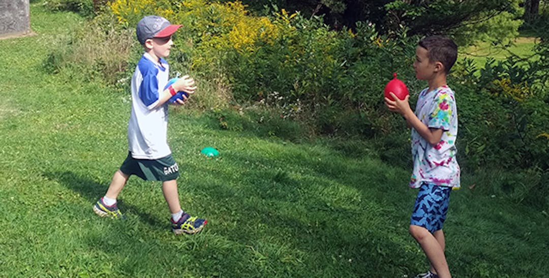 two kids social distanced, playing water balloons