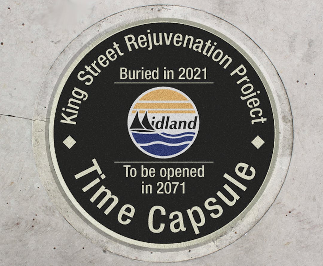 A circular lid for a time capsule that says "King Street Rejuvenation Project Time Capsule, Buried in 2021, To be opened in 2071."