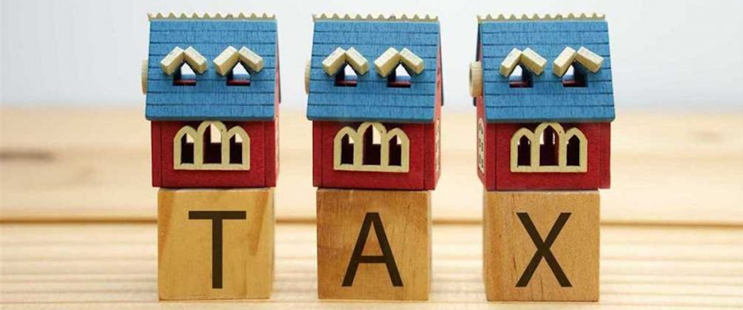 Three small wooden toy houses sat upon wooden alphabet blocks that spell tax.  Image courtesy of www.compass-cpa.com