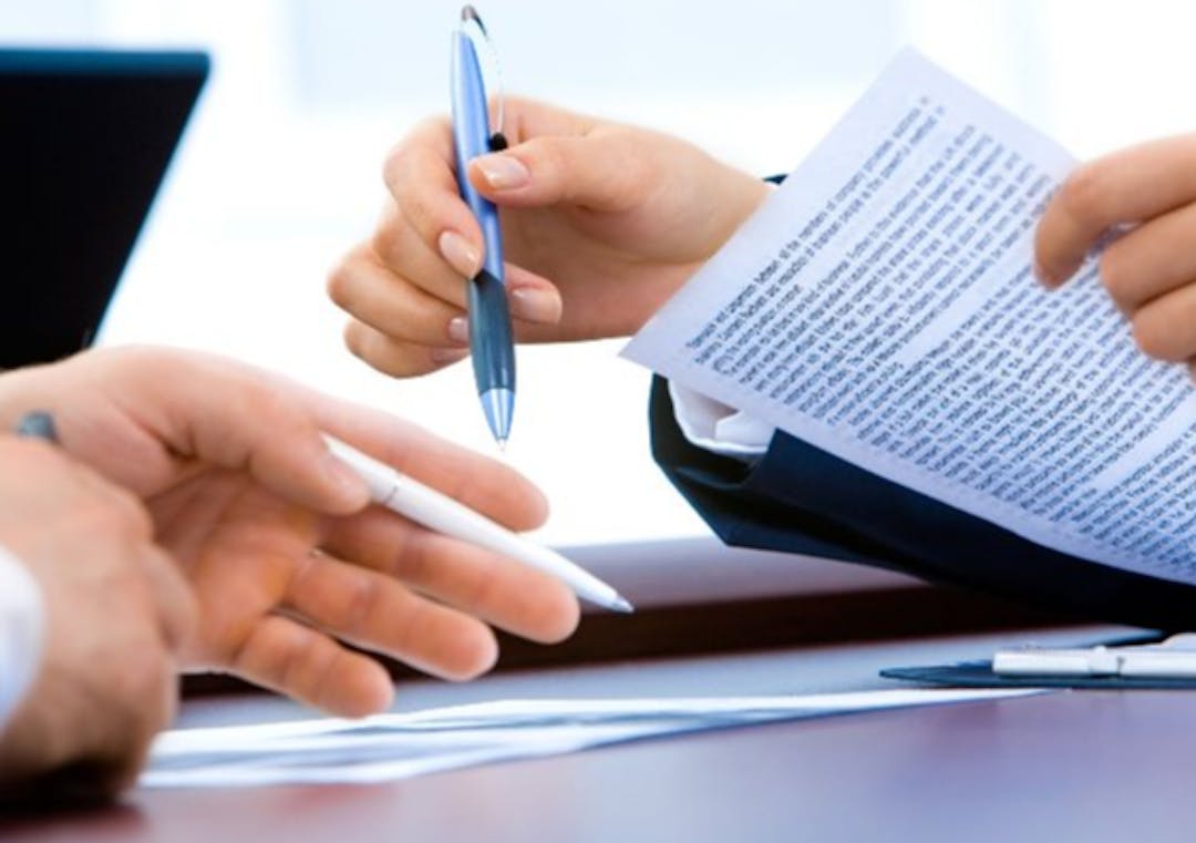 Photo of hands of two people reviewing a document