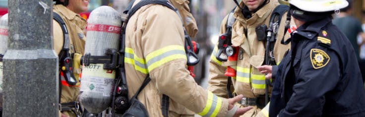 Firefighters standing outside wearing fire gear