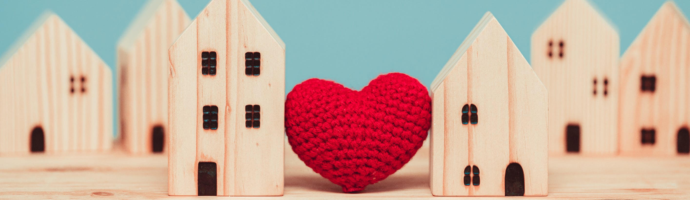 Red heart between two houses in wood model 