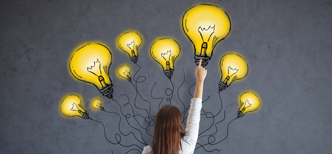 Woman pointing to drawings of lightbulbs on a wall