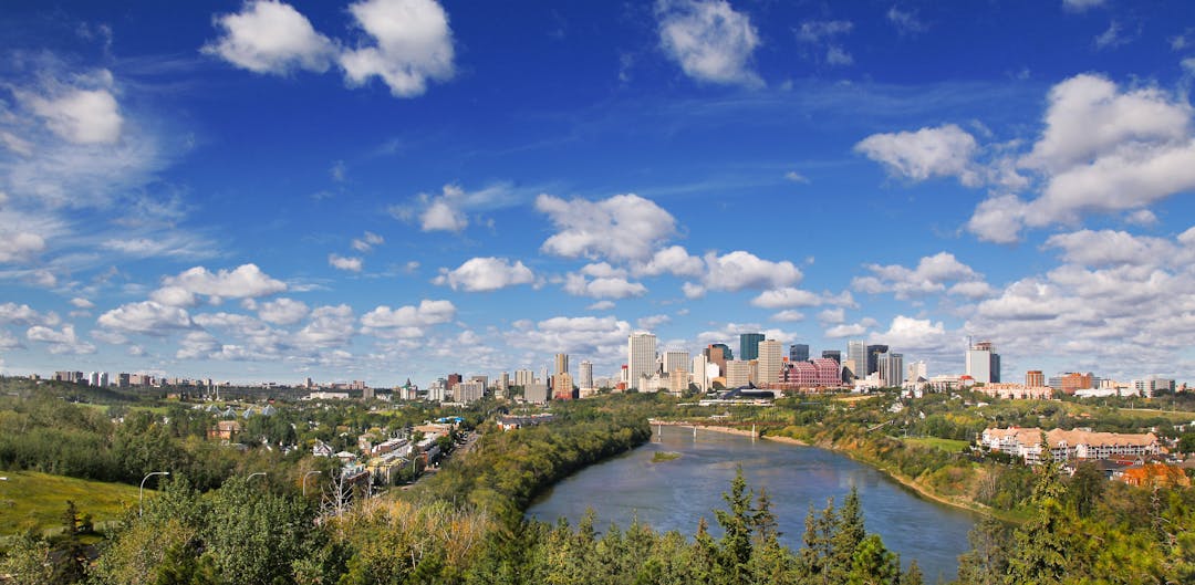 a colour photo of the river valley in summer, with a blue sky and green trees.