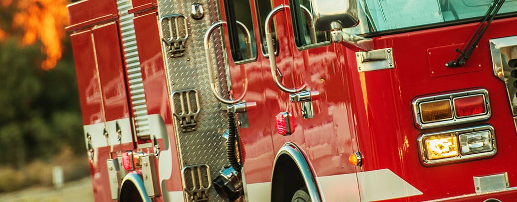 Fire engine facing viewer and angled to the right with wildfire burning in the background