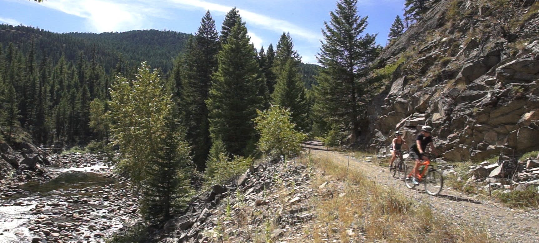 Two mountain bikers ride along the old Kettle Valley Rail grade on a summer day in the Boundary region of the Regional District of Kootenay Boundary