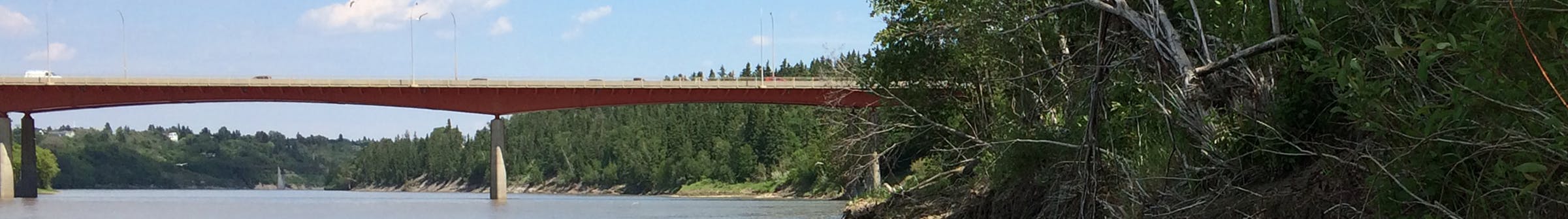 Banner depicting the Capilano Bridge, looking eastward, along the  southern edge of the riverbank where the trail repairs are needed.
