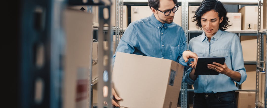 Two people in a room with boxes on shelves