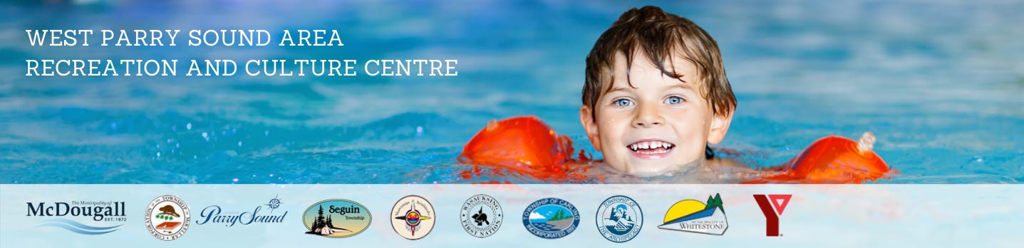 Young boy smiling in pool wearing orange water wings.