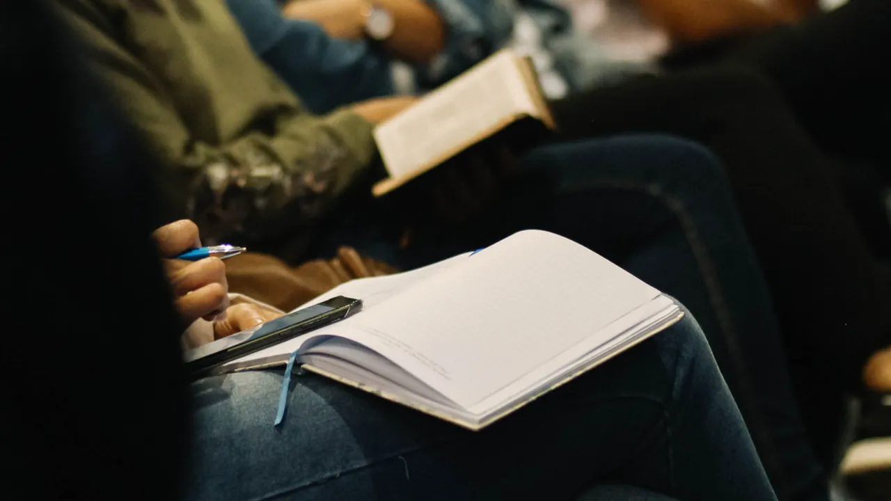 personnes assises en rang avec des livres ouverts sur les genoux