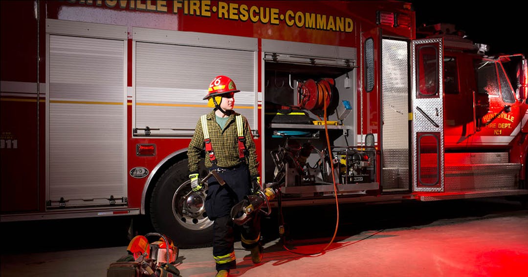 two firefighters water hosing a blaze