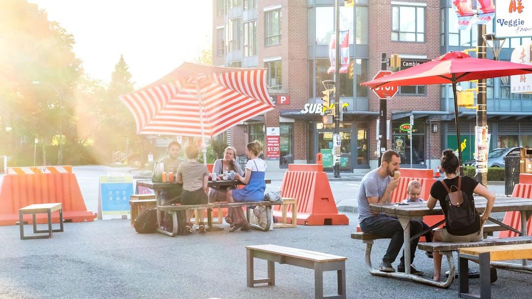 Illustration of a street filled with people on the road protected from cars by traffic barricades.