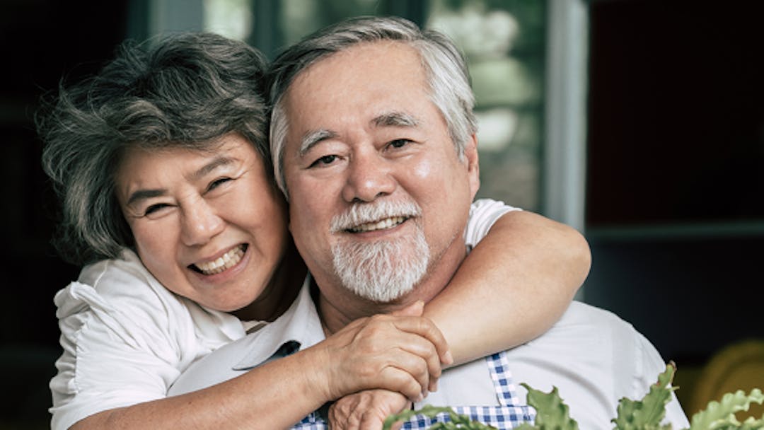 An older couple looking at the camera and smiling