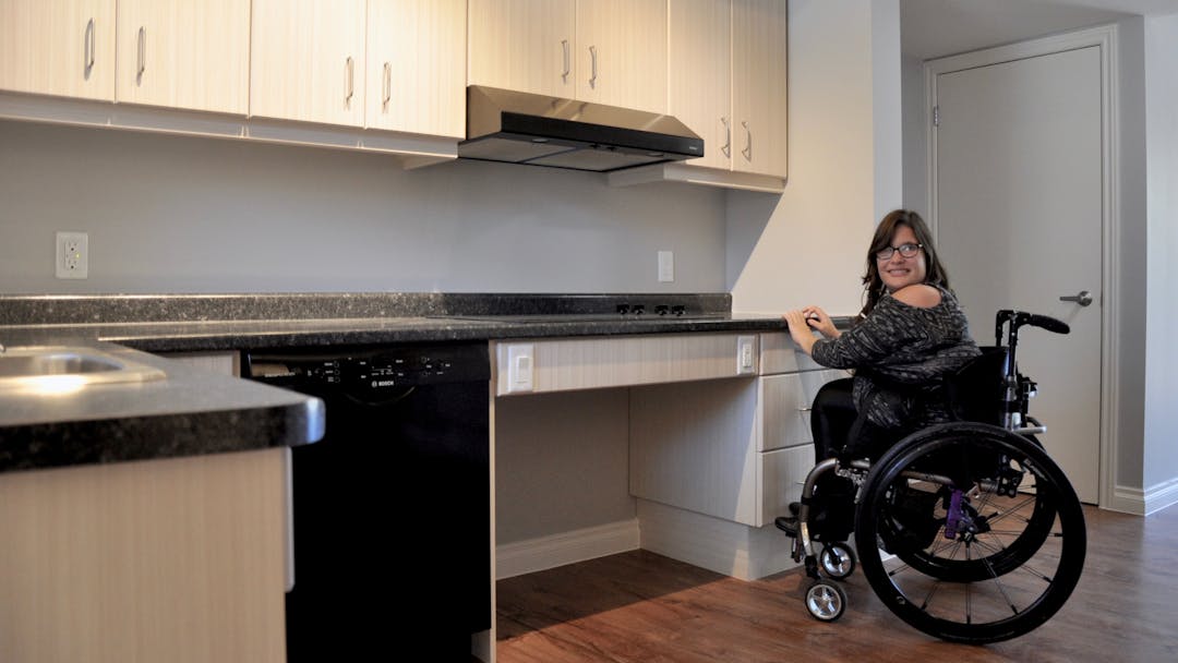 Person who uses a mobility aid testing out a newly renovated accessible kitchen.