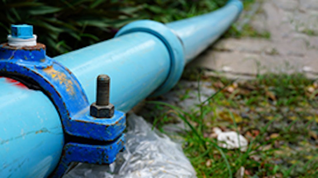 A blue water main pipe resting on grass