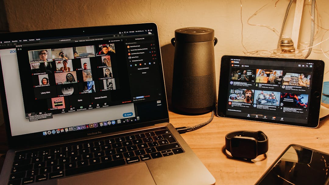 photo of laptop, tablet, smartwatch and cellphone sitting on a desk with a lamp lit in background