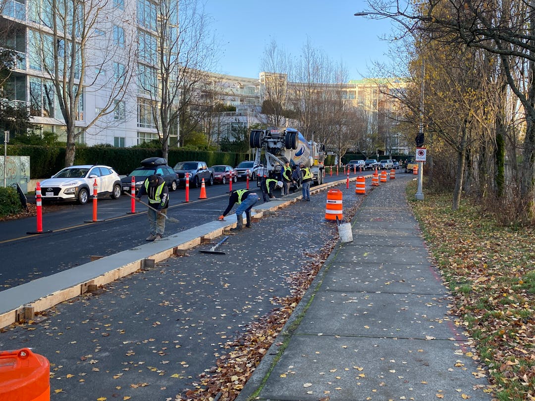Crew of workers pouring concrete to form medians for protected bike lanes.