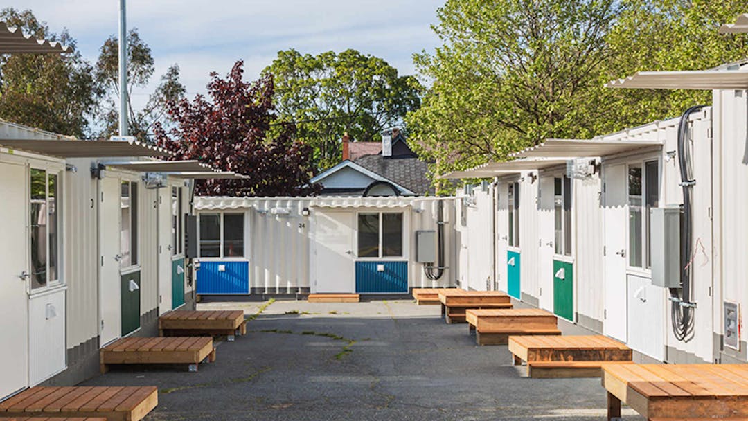 rows of white modular living units with small wooden platforms and steps leading to each door.  