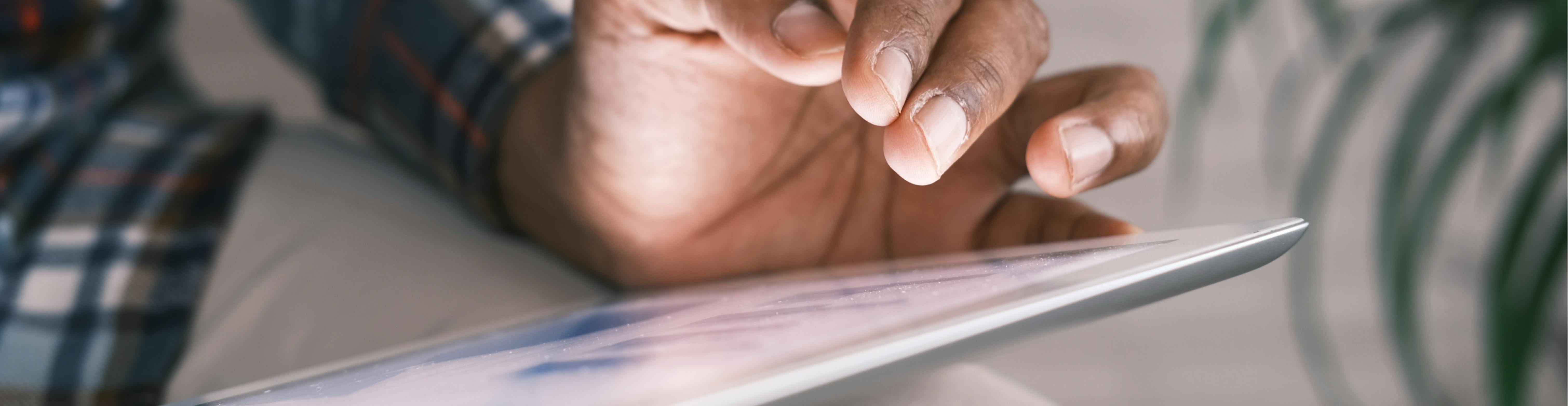 A hand hovering over a tablet.