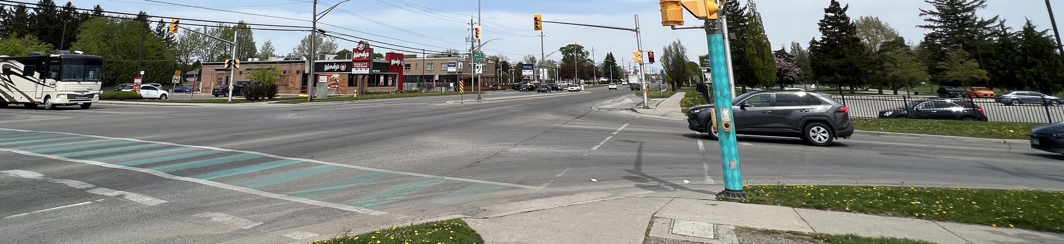 A photo of the intersection and sidewalks at Dundas Street at Highbury Avenue North on a summer day. 