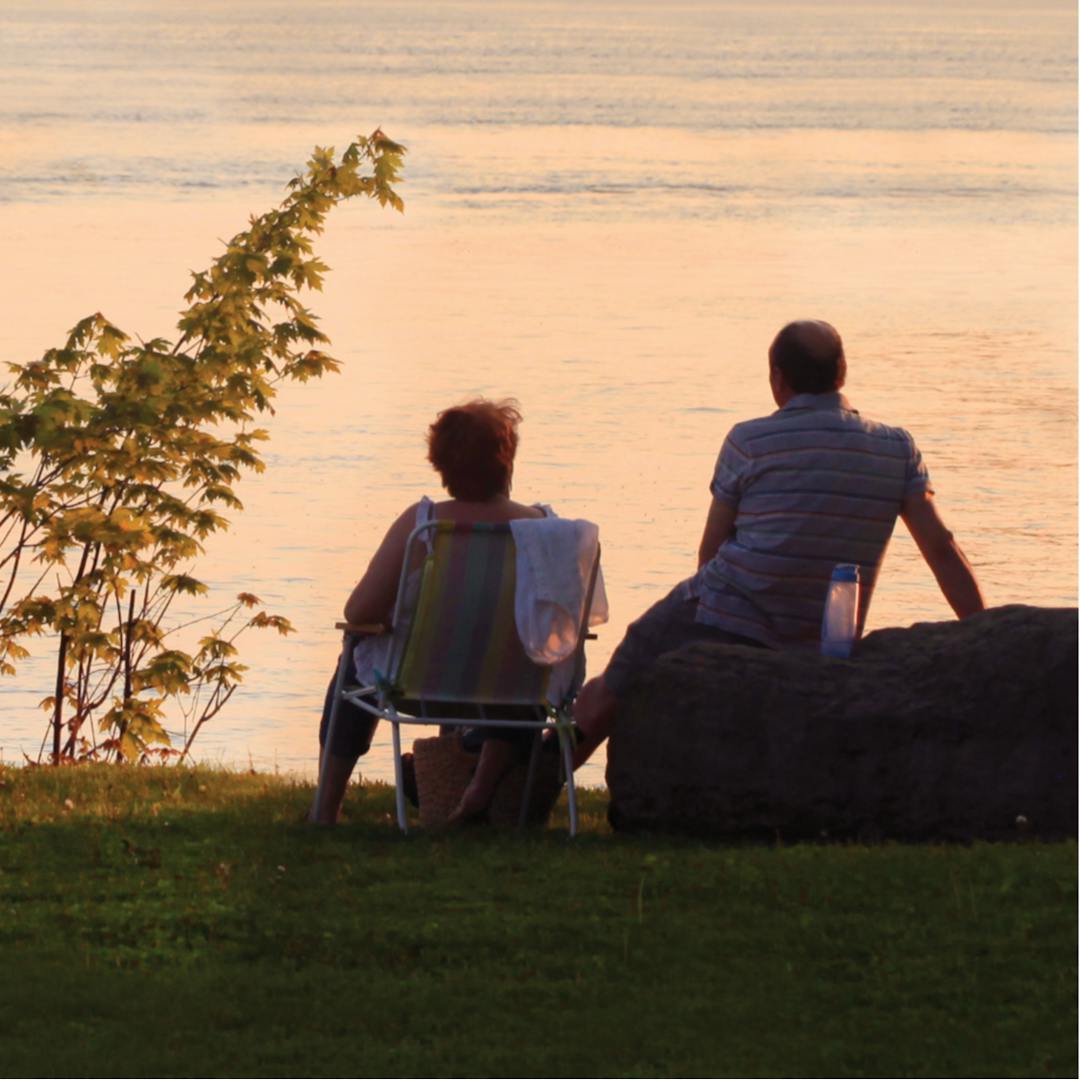 deux personnes de dos assises sur une berge face à une rivière