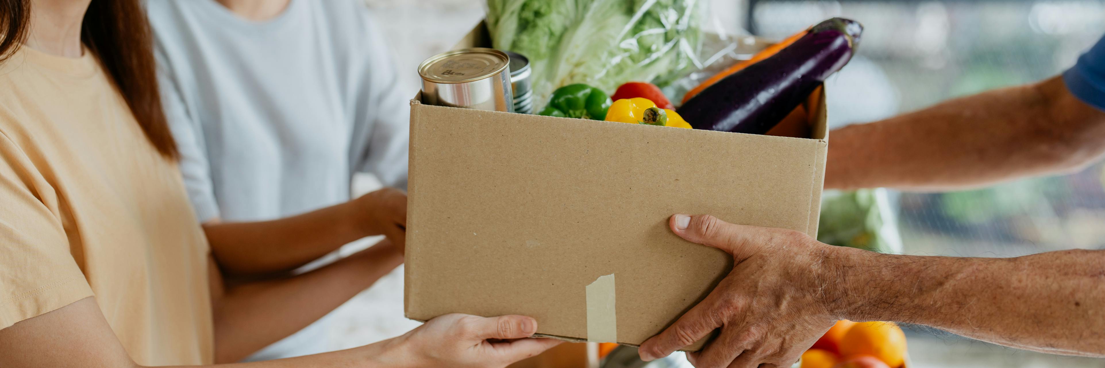 Female volunteers giving free groceries to elderly person at food bank