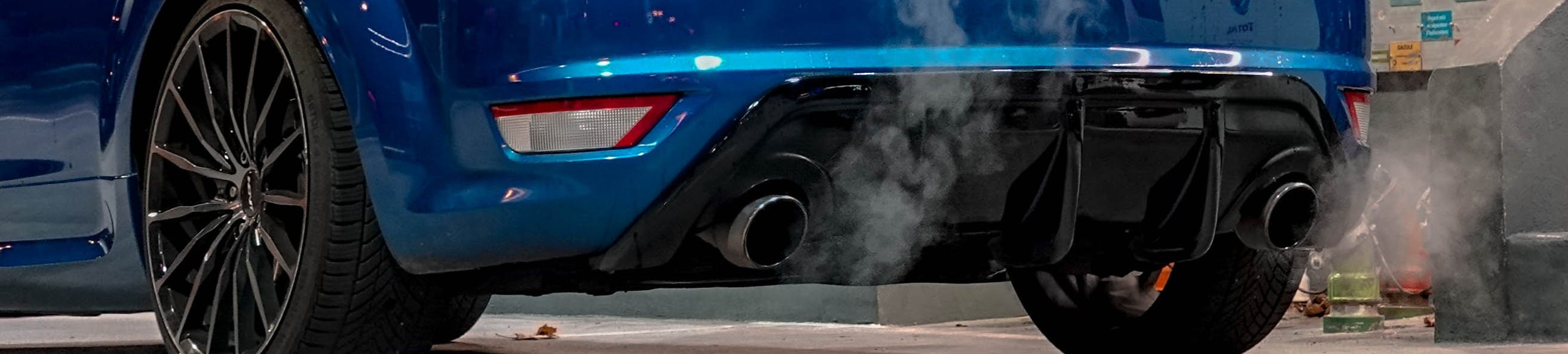Close up photo of a car’s exhaust pipe with emissions coming out as the vehicle idles