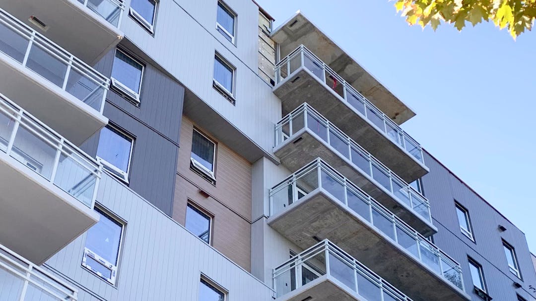 Looking Up from the bottom of a building. Many balconies overhung. 