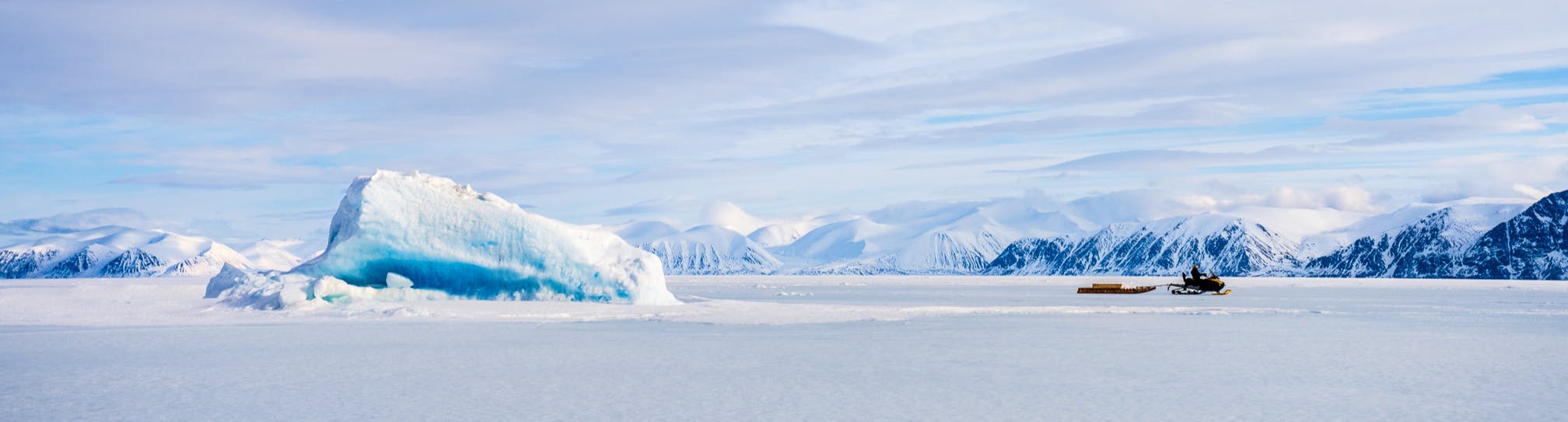 Motoneigiste tirant une cargaison sur la banquise de l'aire marine nationale de conservation de Tallurutiup Imanga